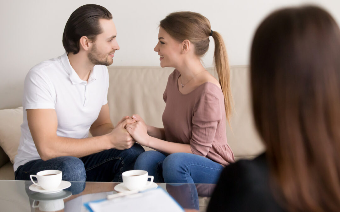 Happy smiling young couple holding hands, consulting psychologis